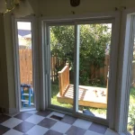 Interior view of white-framed patio doors with outdoor garden